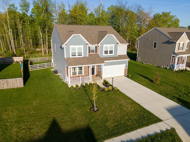 traditional-style home with a porch, fence, concrete driveway, an attached garage, and a shingled roof
