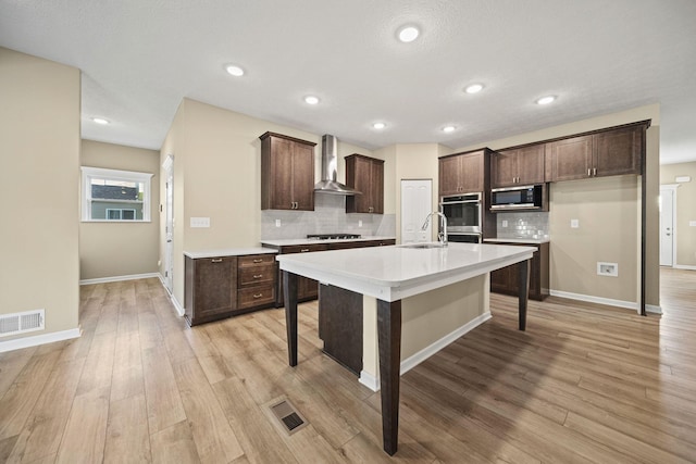 kitchen with visible vents, wall chimney exhaust hood, stainless steel microwave, and backsplash