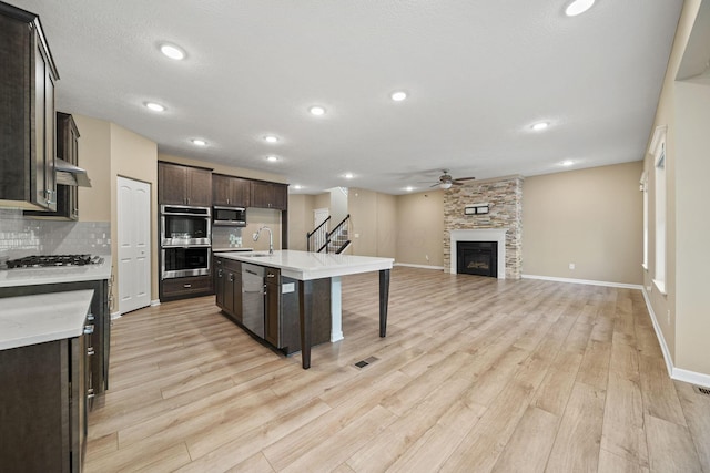 kitchen featuring dark brown cabinets, ceiling fan, light wood-type flooring, a sink, and stainless steel appliances
