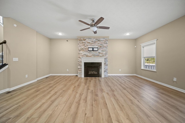 unfurnished living room featuring a ceiling fan, baseboards, light wood finished floors, and a fireplace