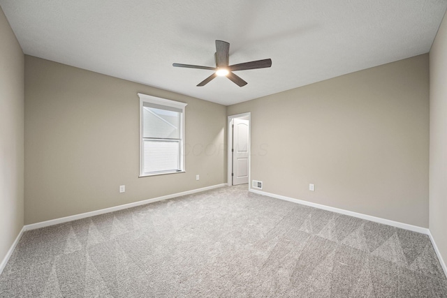 carpeted spare room featuring ceiling fan, visible vents, and baseboards