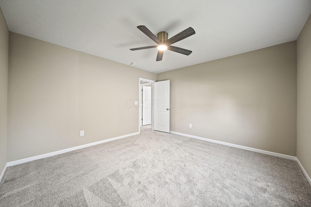 carpeted empty room featuring a ceiling fan and baseboards