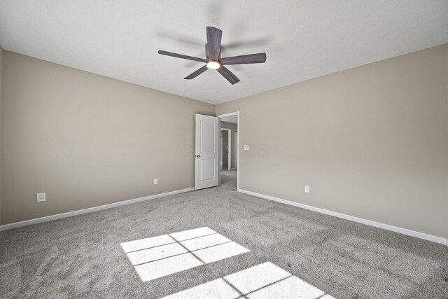 carpeted empty room with ceiling fan and baseboards