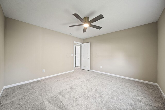 carpeted empty room featuring a ceiling fan and baseboards