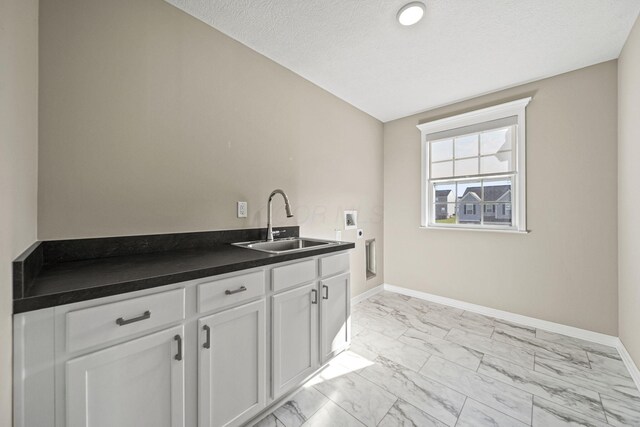 kitchen with a sink, dark countertops, baseboards, and marble finish floor