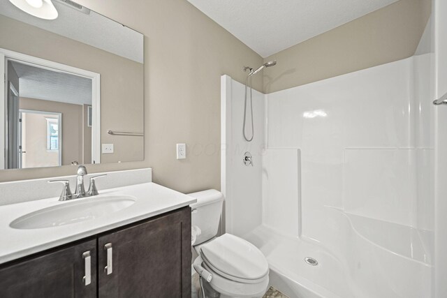 full bathroom featuring toilet, walk in shower, visible vents, and vanity