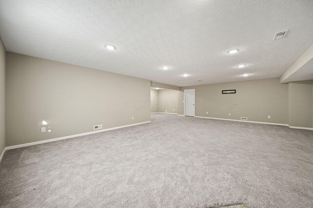 finished below grade area featuring visible vents, carpet flooring, and baseboards