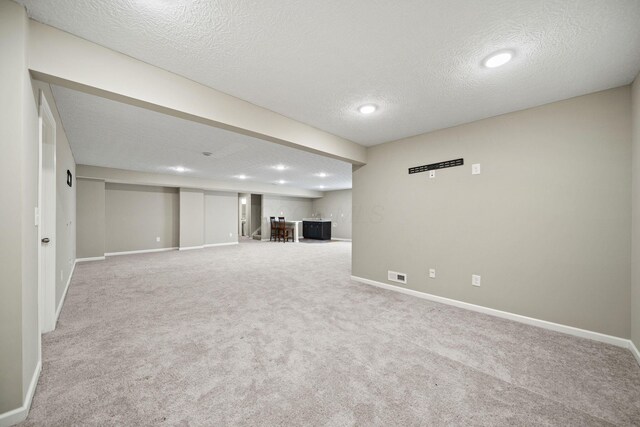 finished basement with bar, a textured ceiling, visible vents, baseboards, and carpet flooring