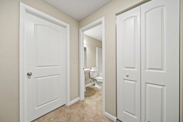 corridor featuring baseboards and light carpet