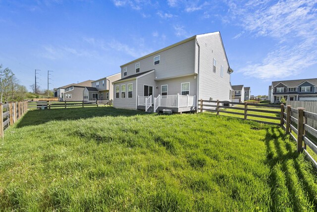 rear view of property featuring a lawn, a fenced backyard, and a deck