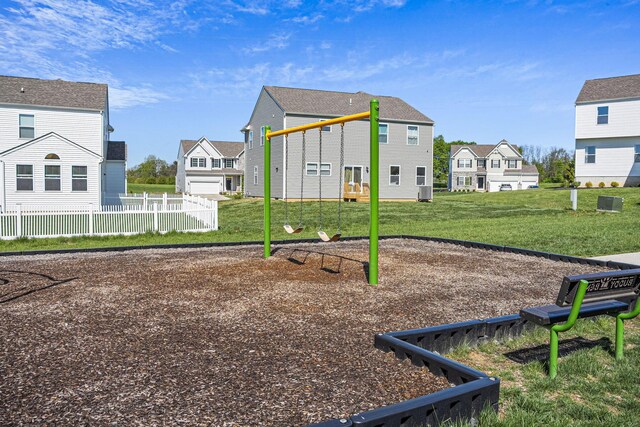 community play area featuring a lawn, central AC, fence, and a residential view
