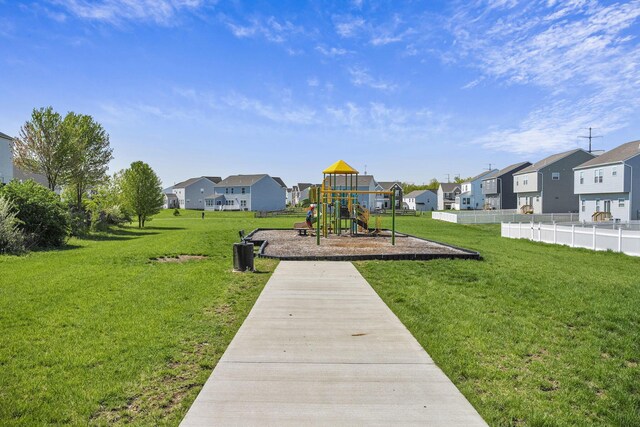 communal playground featuring a yard, fence, and a residential view