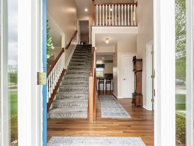 foyer entrance with plenty of natural light, wood finished floors, stairway, and a towering ceiling