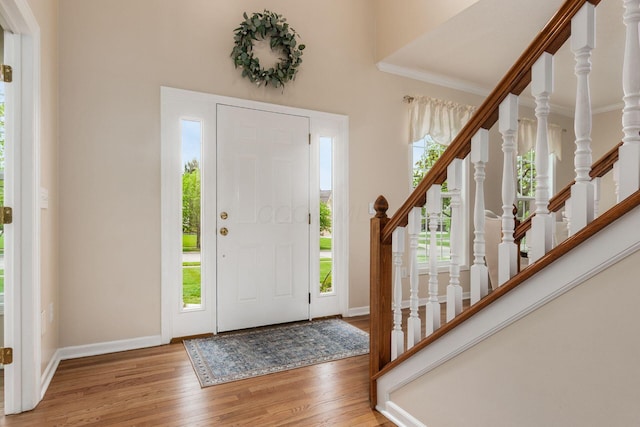 entryway featuring baseboards, ornamental molding, wood finished floors, and stairway