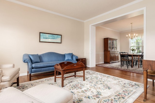 living room with an inviting chandelier, baseboards, ornamental molding, and wood finished floors