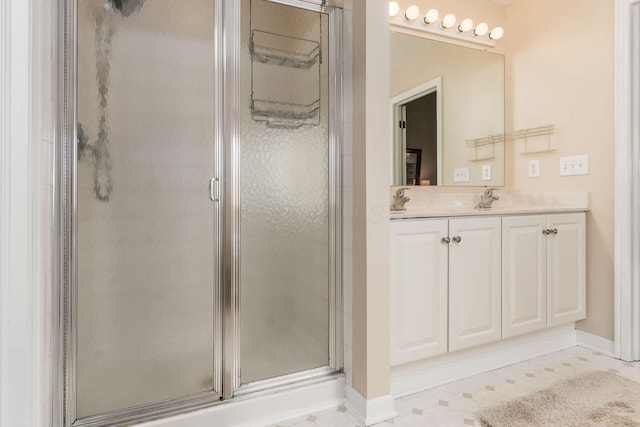 full bathroom with baseboards, double vanity, a sink, and a stall shower