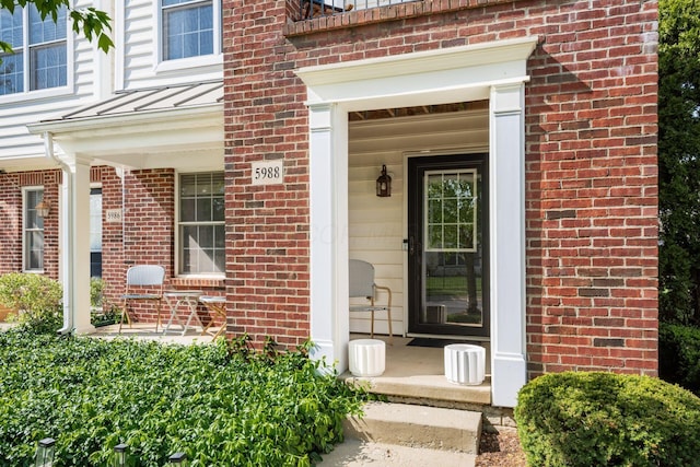 doorway to property with covered porch and brick siding