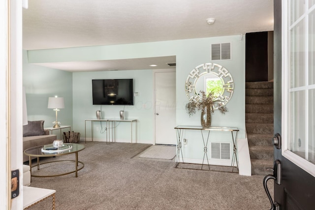 carpeted living area with stairway, baseboards, and visible vents