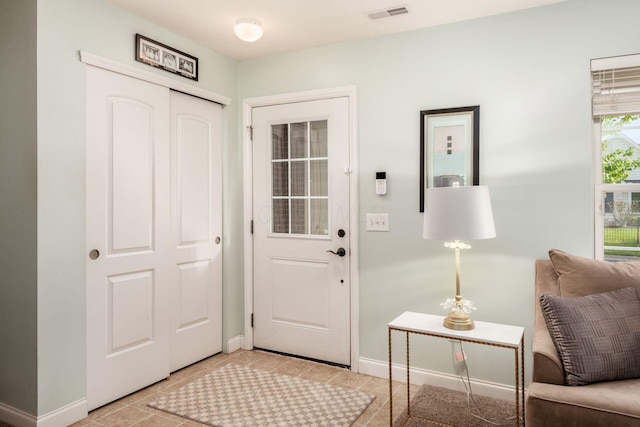 foyer entrance featuring baseboards, visible vents, and light tile patterned floors