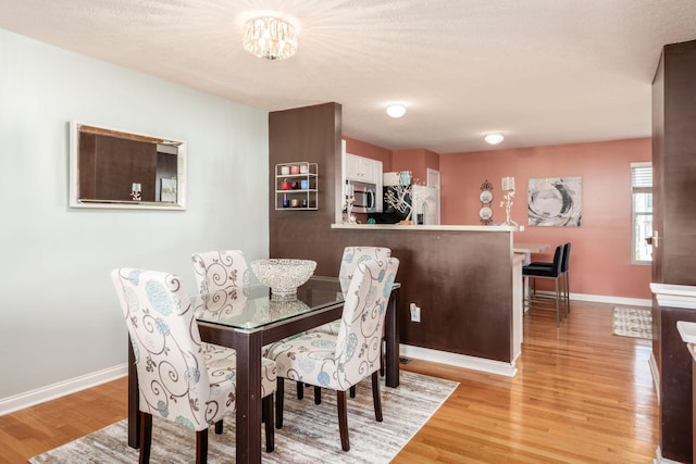 dining area featuring baseboards, light wood-style flooring, and an inviting chandelier