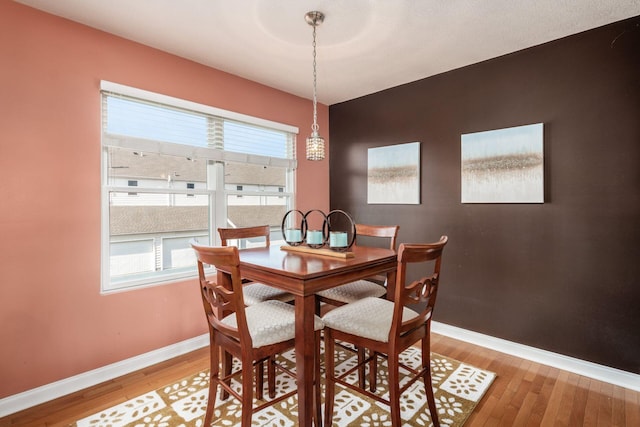 dining space featuring baseboards, light wood-style floors, and a healthy amount of sunlight