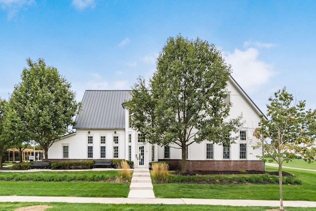 modern inspired farmhouse with brick siding, a front lawn, and french doors
