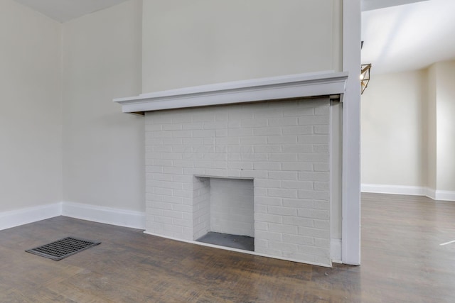 room details with a brick fireplace, baseboards, visible vents, and wood finished floors