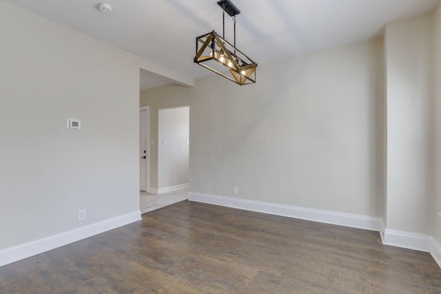 unfurnished dining area with an inviting chandelier, baseboards, and dark wood-style floors