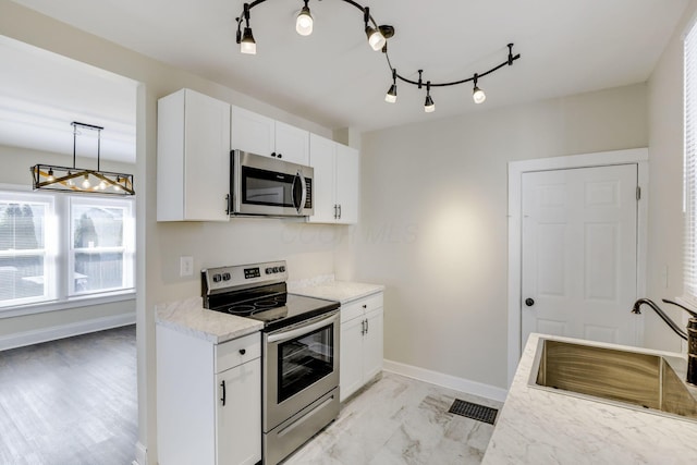kitchen with visible vents, a sink, white cabinets, a notable chandelier, and stainless steel appliances