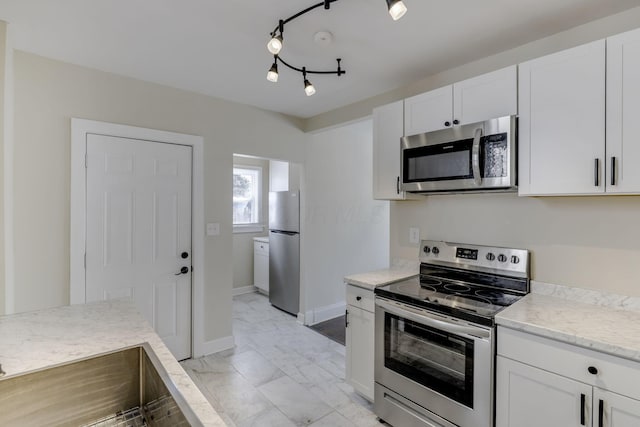 kitchen featuring white cabinets, baseboards, appliances with stainless steel finishes, and marble finish floor