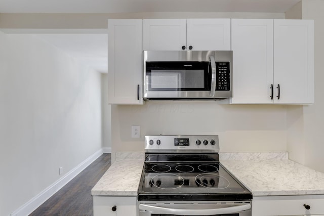 kitchen featuring appliances with stainless steel finishes, baseboards, dark wood finished floors, and white cabinetry