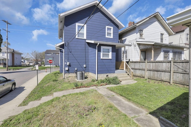 back of house featuring fence, a lawn, and a residential view