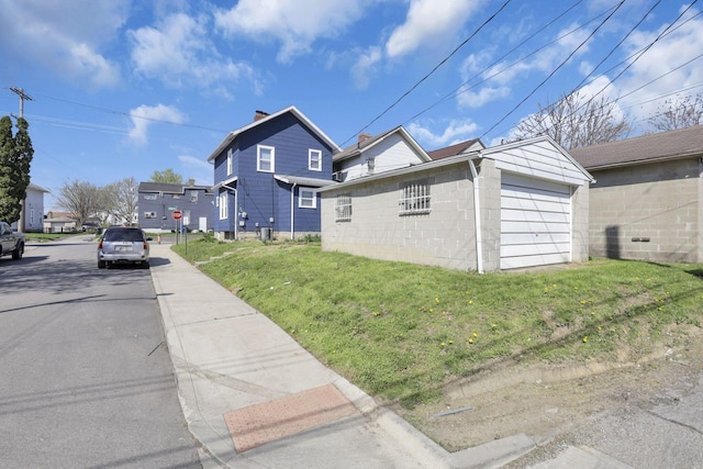 view of side of property with a yard, an attached garage, driveway, and an outbuilding