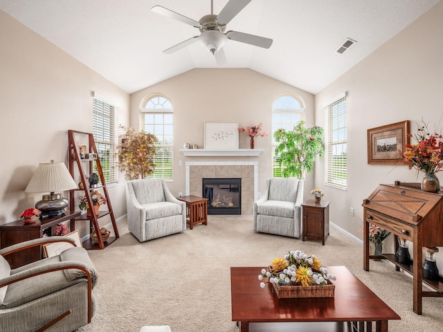 carpeted living area featuring visible vents, lofted ceiling, baseboards, ceiling fan, and a tiled fireplace