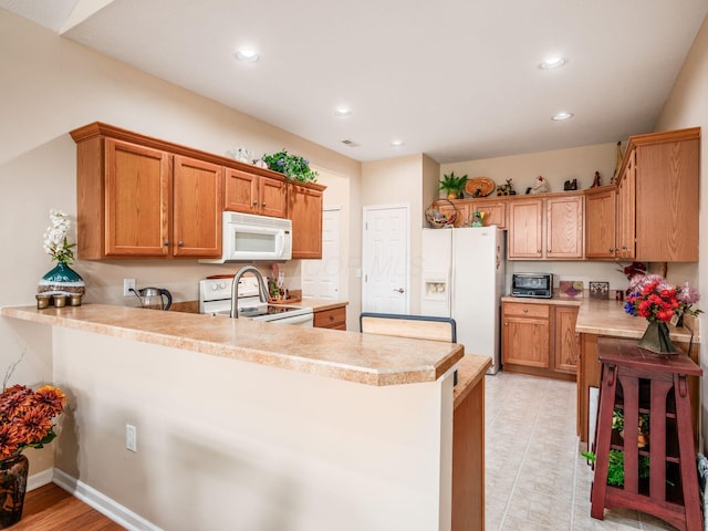 kitchen with white appliances, a peninsula, recessed lighting, and light countertops