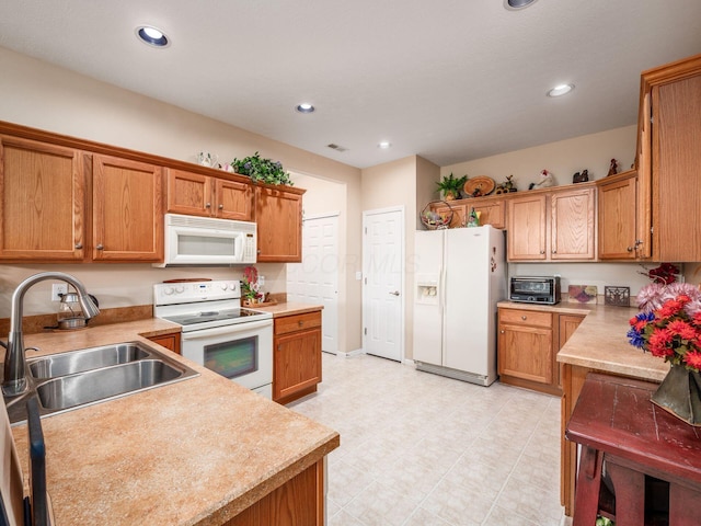 kitchen with white appliances, recessed lighting, a sink, and light countertops