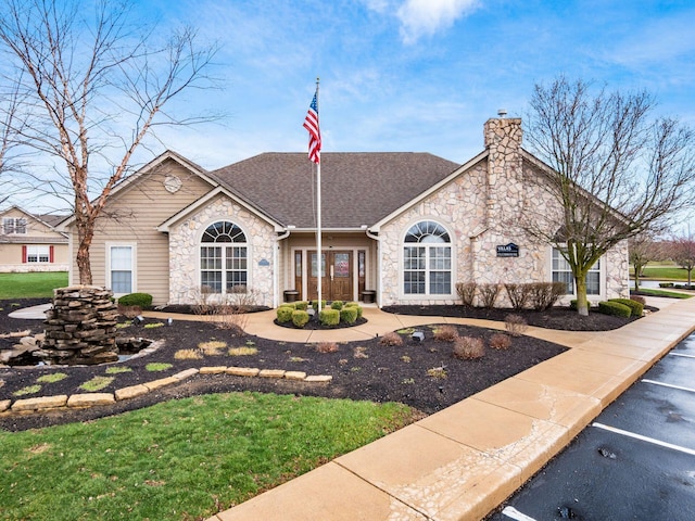 view of front of home with a chimney, a shingled roof, and stone siding