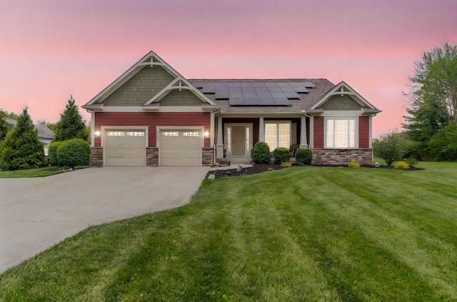 craftsman-style house featuring a garage, a front lawn, stone siding, roof mounted solar panels, and driveway