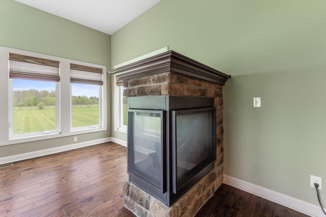 details featuring a stone fireplace, baseboards, and wood finished floors