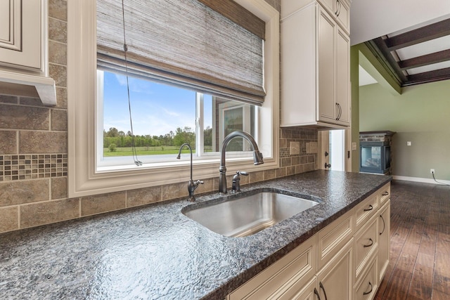 kitchen featuring a sink, baseboards, tasteful backsplash, and dark wood-type flooring