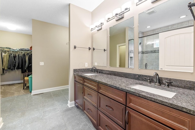 full bathroom featuring a sink, baseboards, a stall shower, and visible vents