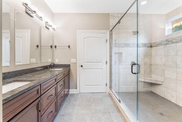 full bathroom with a sink, baseboards, a shower stall, and double vanity