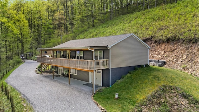 24796 E Fork Rd, Laurelville, OH 43135 - view of front of home featuring a deck, an attached garage, a wooded view, and aphalt driveway
