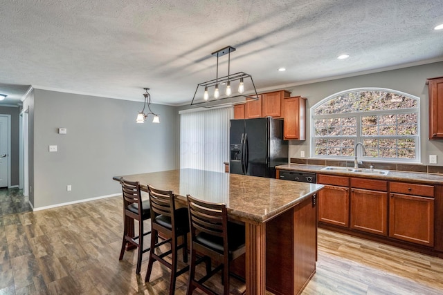24796 E Fork Rd, Laurelville, OH 43135 - kitchen with brown cabinetry, a kitchen island, a textured ceiling, a sink, and black appliances
