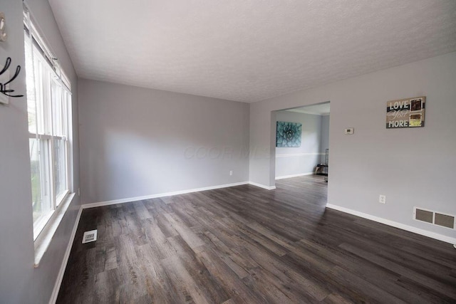 unfurnished room featuring baseboards, dark wood-type flooring, and visible vents