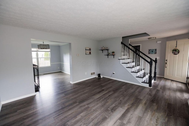 unfurnished living room with stairway, baseboards, dark wood-style floors, and a textured ceiling