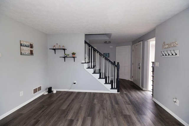 entrance foyer with stairway, baseboards, wood finished floors, and visible vents