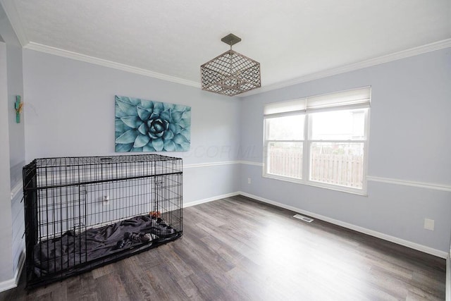 interior space with visible vents, baseboards, crown molding, and wood finished floors