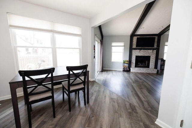 dining space featuring a brick fireplace, baseboards, and dark wood-type flooring