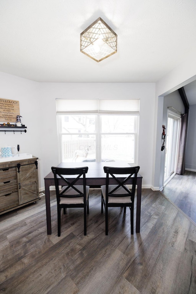 dining space with baseboards and dark wood finished floors